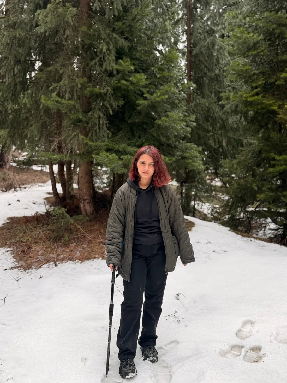 Hadia on a snowy forest trail with a trekking pole