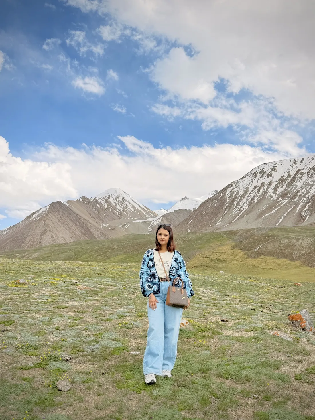 Hadia standing on an alpine plateau below snow-capped peaks